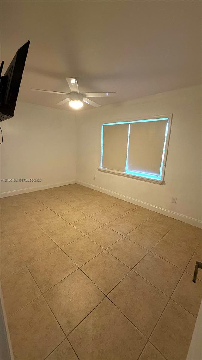Neutral-toned tile flooring, ceiling fan with integrated lighting, and a window with blinds
