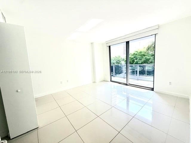 Interior space featuring large-format ceramic tile flooring, floor-to-ceiling glass sliding door, and built-in closet