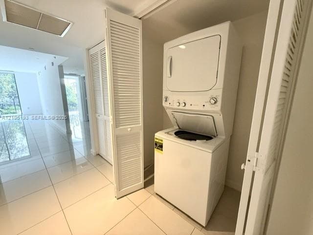 Stacked laundry unit enclosed by louvered bi-fold doors, set against large-format tile flooring