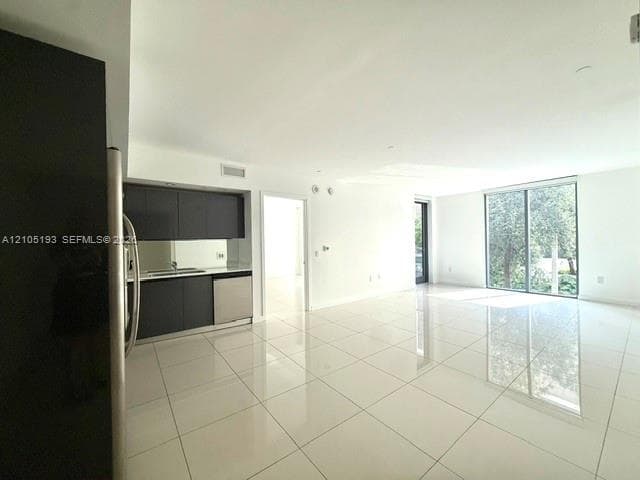 Open-concept interior featuring large-format tile flooring, matte dark cabinetry, integrated stainless steel appliances, and floor-to-ceiling glass sliding doors