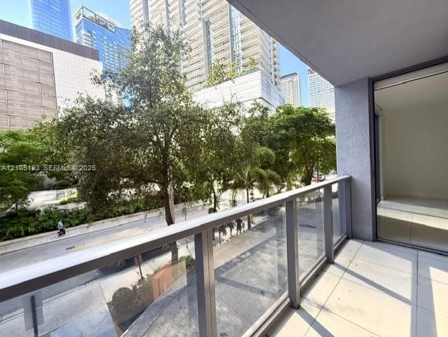 Covered balcony featuring tile flooring and a glass-paneled railing