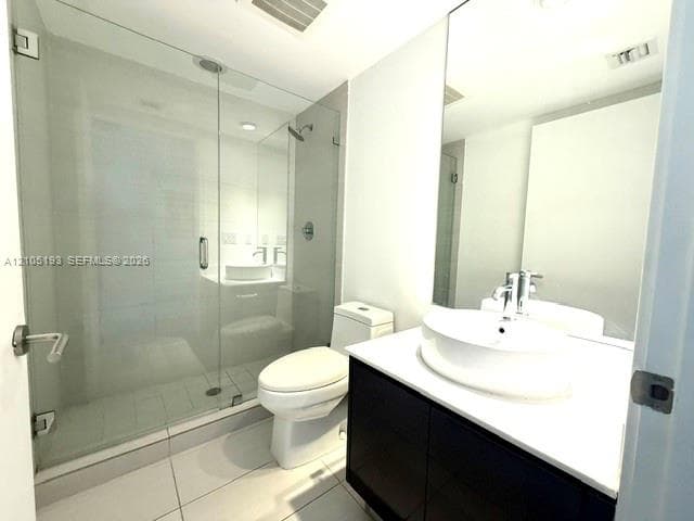 Bathroom featuring a frameless glass-enclosed shower, a dark-finish vanity with a white countertop, and a vessel sink with a chrome faucet