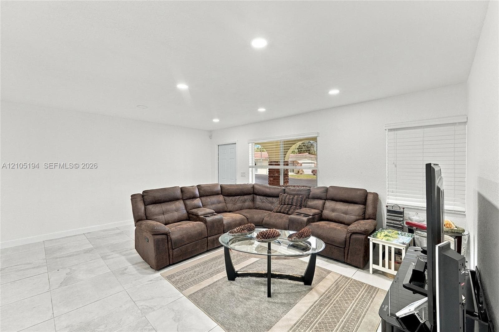 Large-format tile flooring, recessed ceiling lighting, and horizontal window blinds