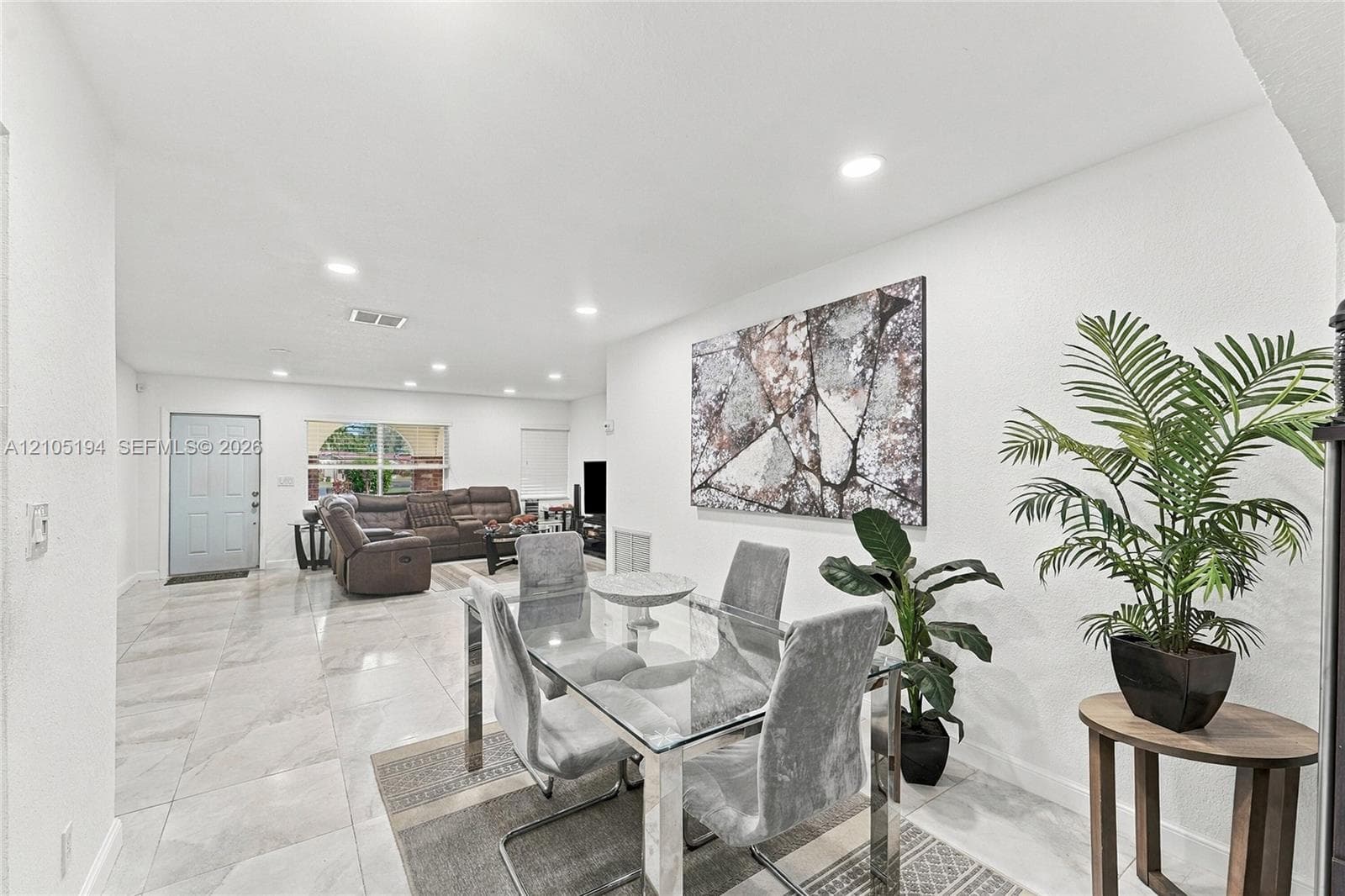 Neutral-toned stone-finish flooring and recessed lighting throughout an open-concept interior featuring smooth wall finishes
