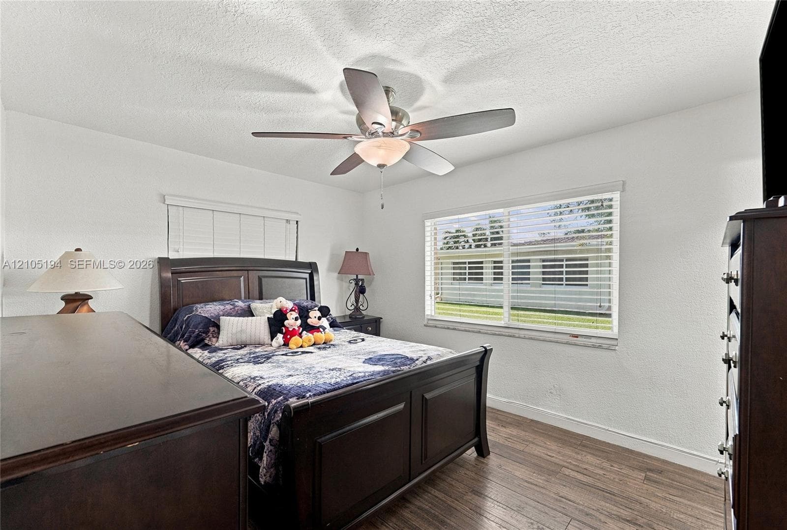 Bedroom featuring wood-finish flooring, a ceiling fan with integrated lighting, and horizontal window blinds