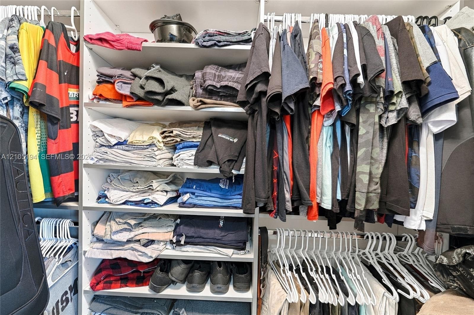 Custom walk-in closet featuring white laminate shelving, multiple tiered storage levels, and integrated hanging rods