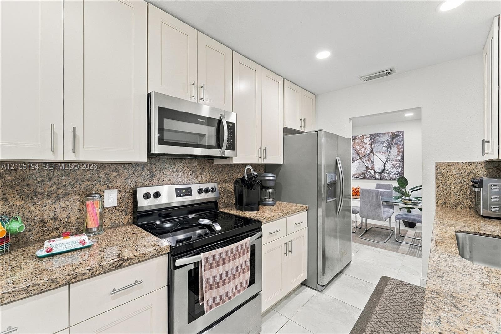 Kitchen featuring white cabinetry, stone-surface countertops, tile flooring, and stainless steel appliances