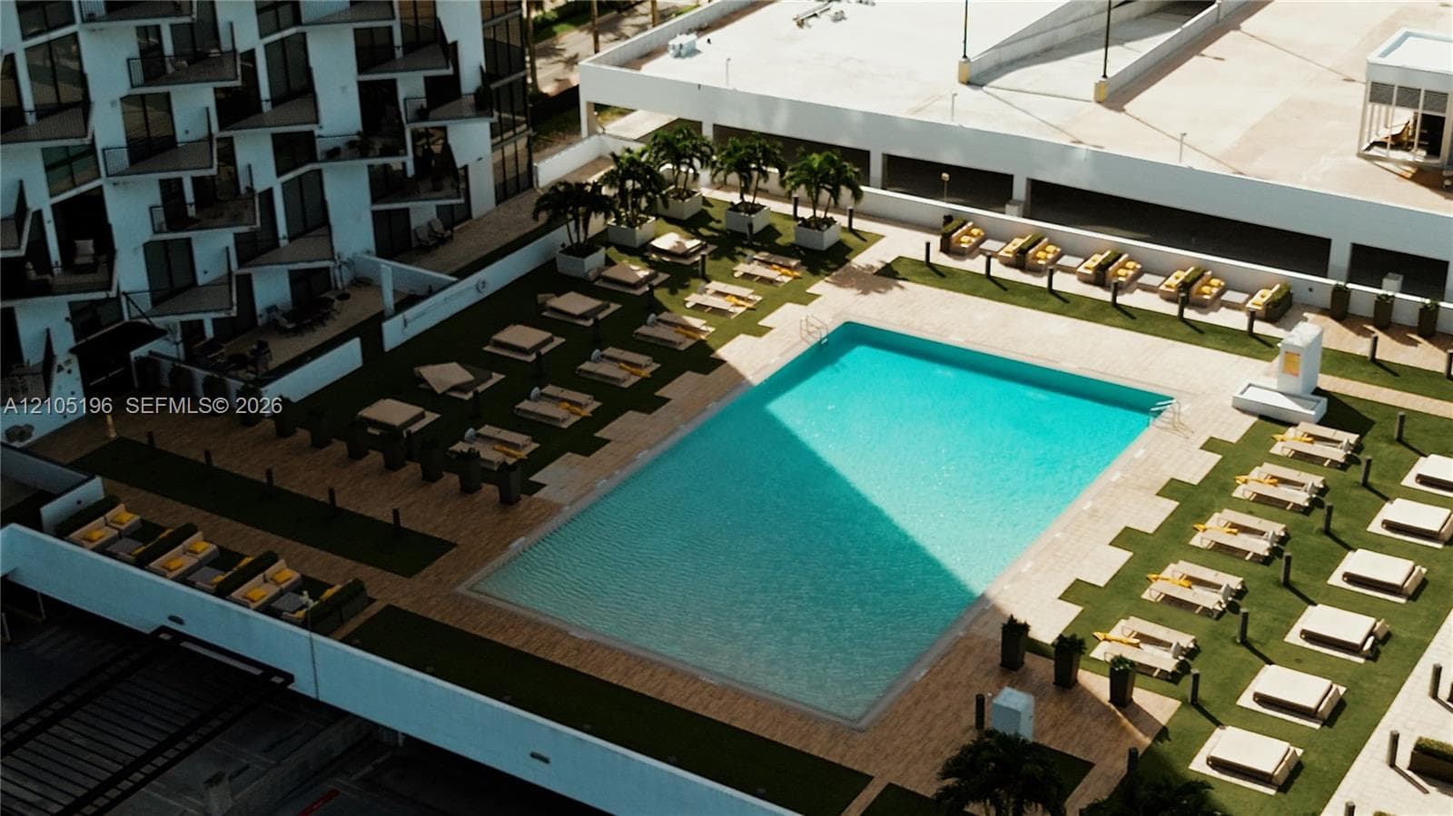 Expansive outdoor pool area featuring a rectangular pool, artificial turf, and multiple designated lounging zones