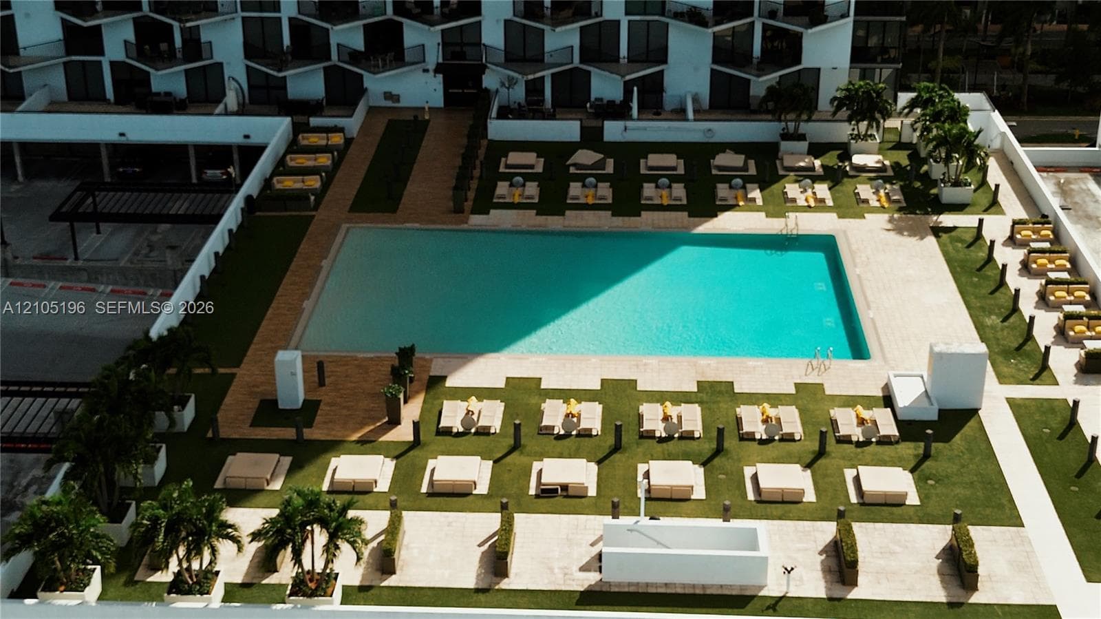 Expansive rectangular pool, surrounded by a paved deck and manicured green spaces