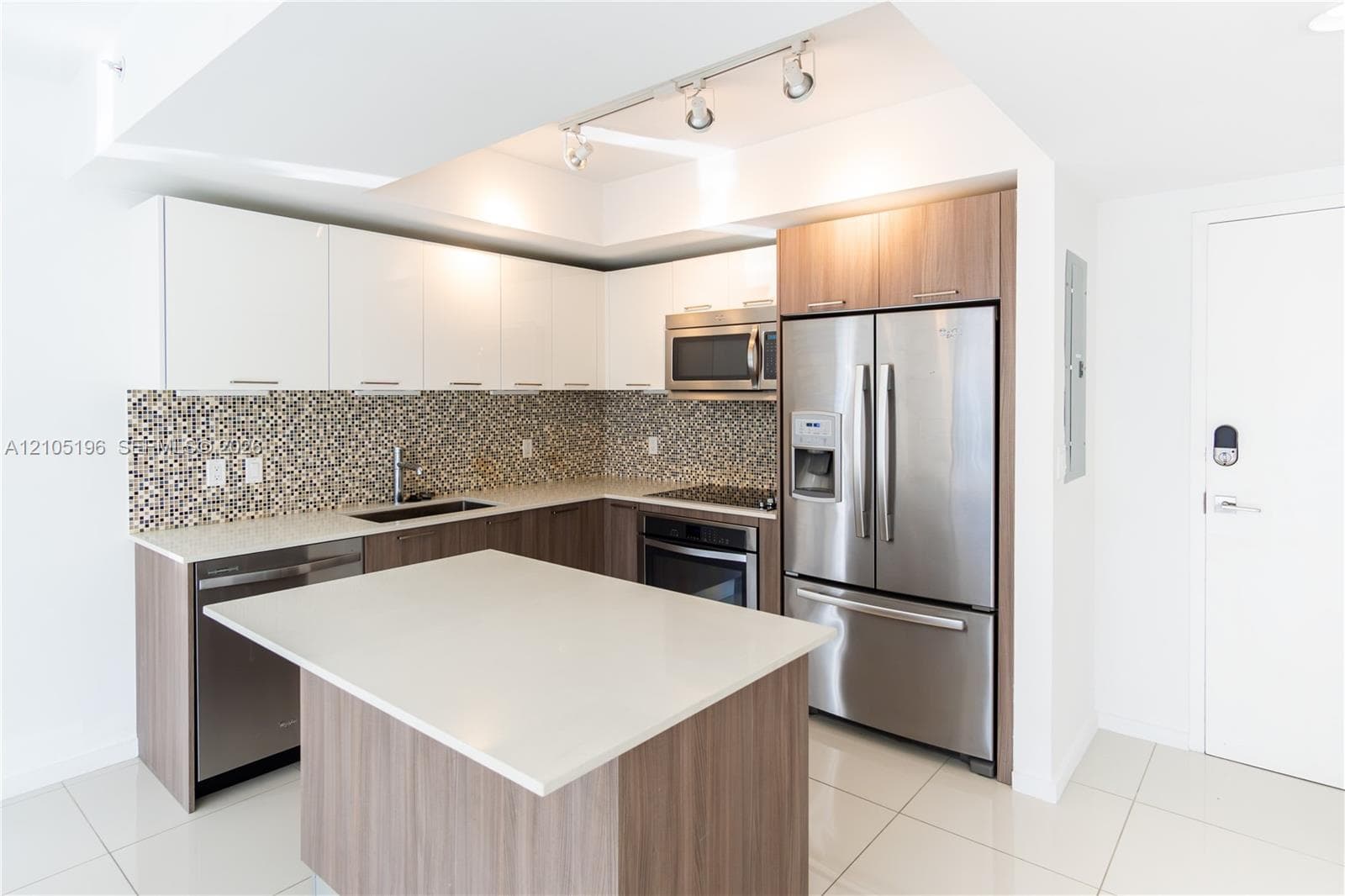 Kitchen featuring a central island, stainless steel appliances, white flat-panel upper cabinetry, wood-finish lower cabinetry, and a mosaic tile backsplash