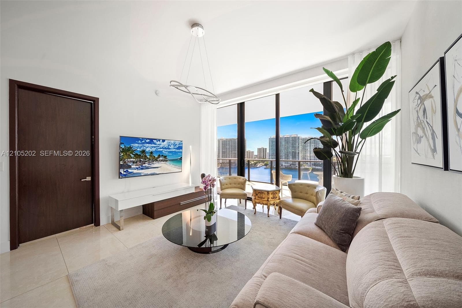 Living area featuring floor-to-ceiling windows, polished tile flooring, a modern sculptural chandelier, and a solid wood entry door