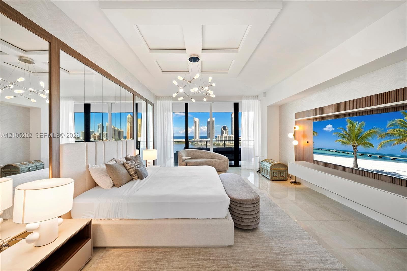 Coffered ceiling with integrated light fixture, mirrored wall panels, built-in media console with wood-slat detailing, polished tile flooring, and floor-to-ceiling windows