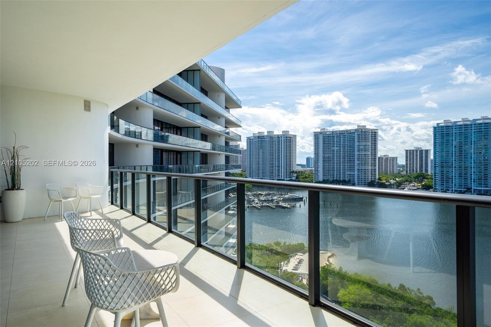 Expansive covered balcony featuring large-format stone flooring and a full-height glass railing system with sleek metal frames