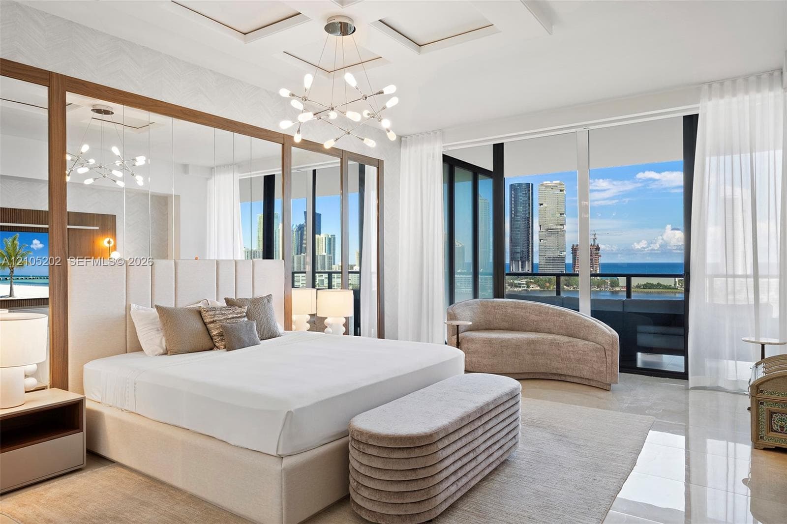 Floor-to-ceiling windows, full-wall mirror paneling, coffered ceiling, modern multi-arm chandelier, and polished tile flooring