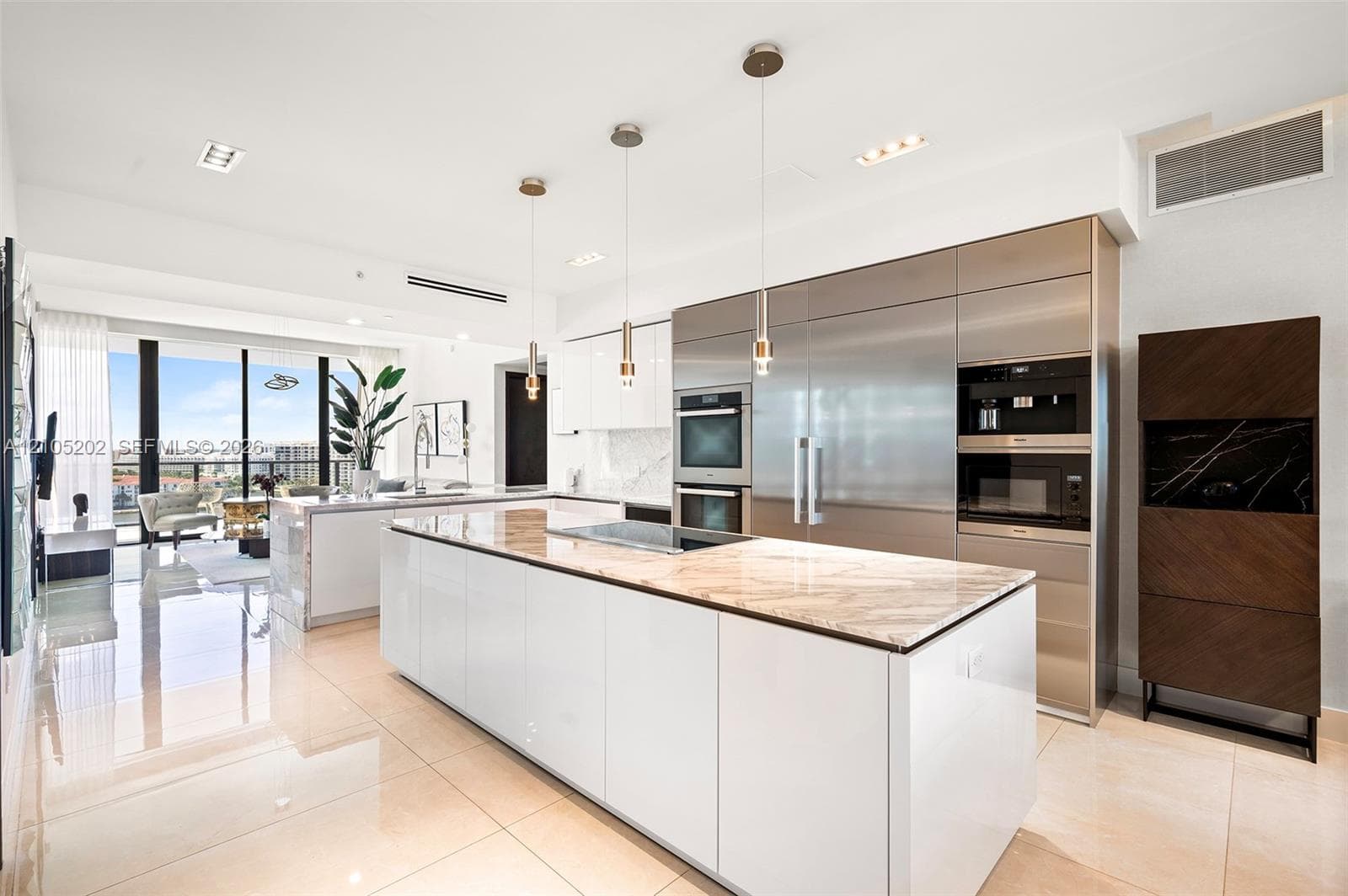 Kitchen featuring a central island with stone countertop, high-gloss cabinetry, integrated stainless steel appliances, built-in coffee station, and glass pendant lighting