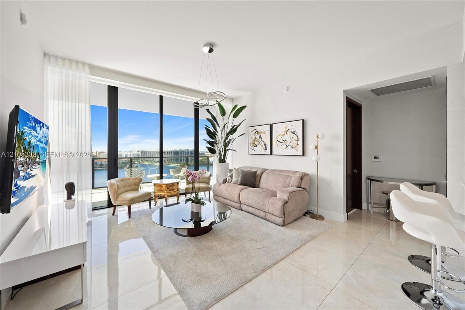 Floor-to-ceiling glass windows, polished tile flooring, integrated pendant lighting, and a glass-railed balcony