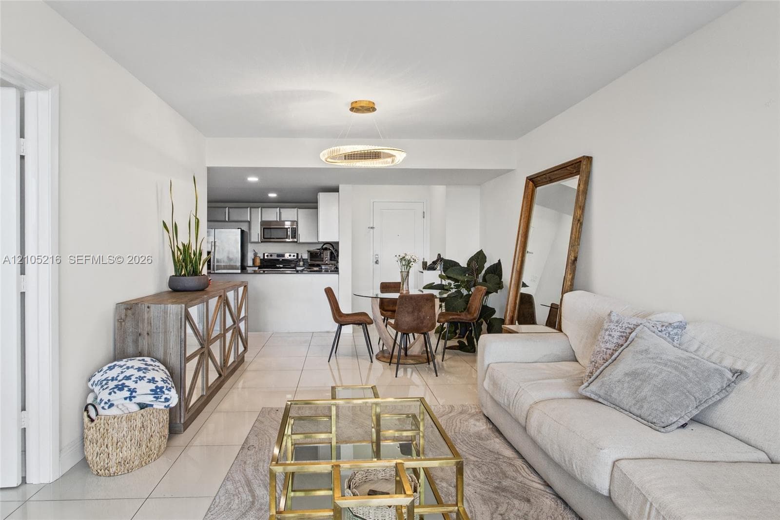 Open-concept living space with tile flooring throughout, featuring a kitchen with stainless steel appliances and a dining area