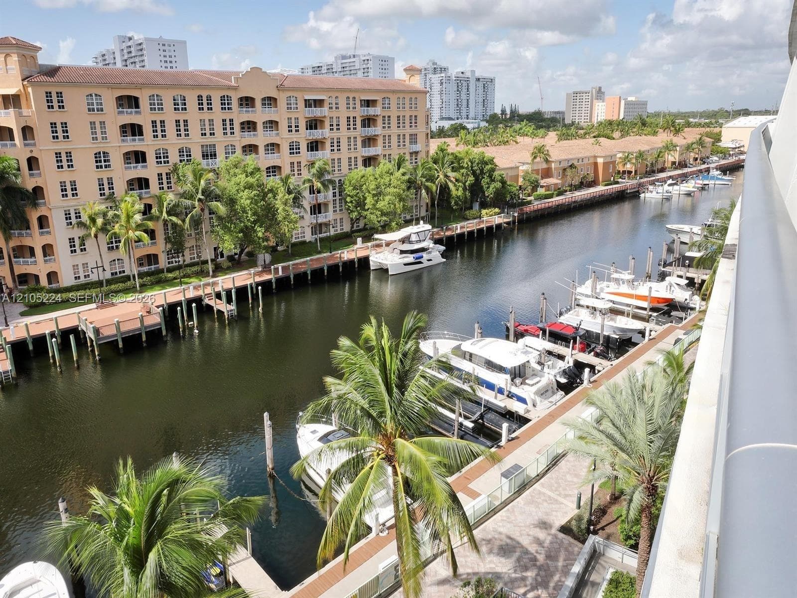 Waterfront canal with dock access, mature palm trees, and established adjacent buildings