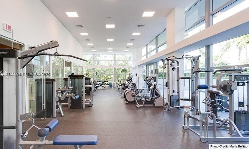 Fitness center featuring expansive floor-to-ceiling windows, numerous exercise machines, resilient flooring, and recessed square lighting