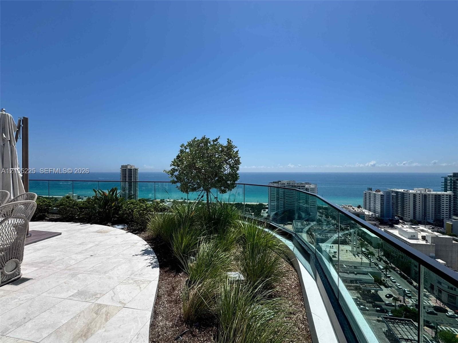 Curved terrace with tiled flooring, glass railing, and integrated planters