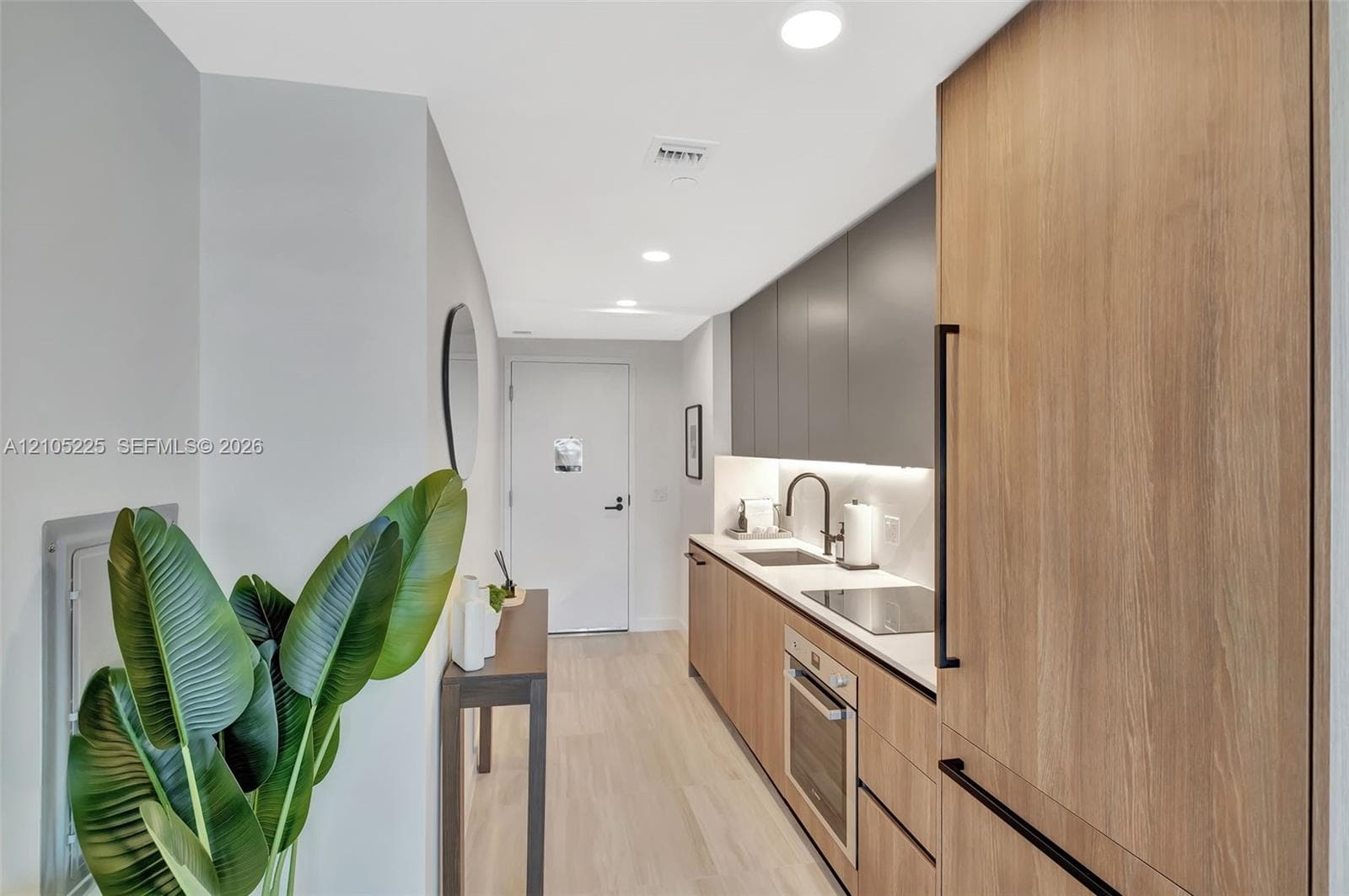 Integrated kitchen with wood-finish cabinetry, solid surface countertops, and stainless steel appliances