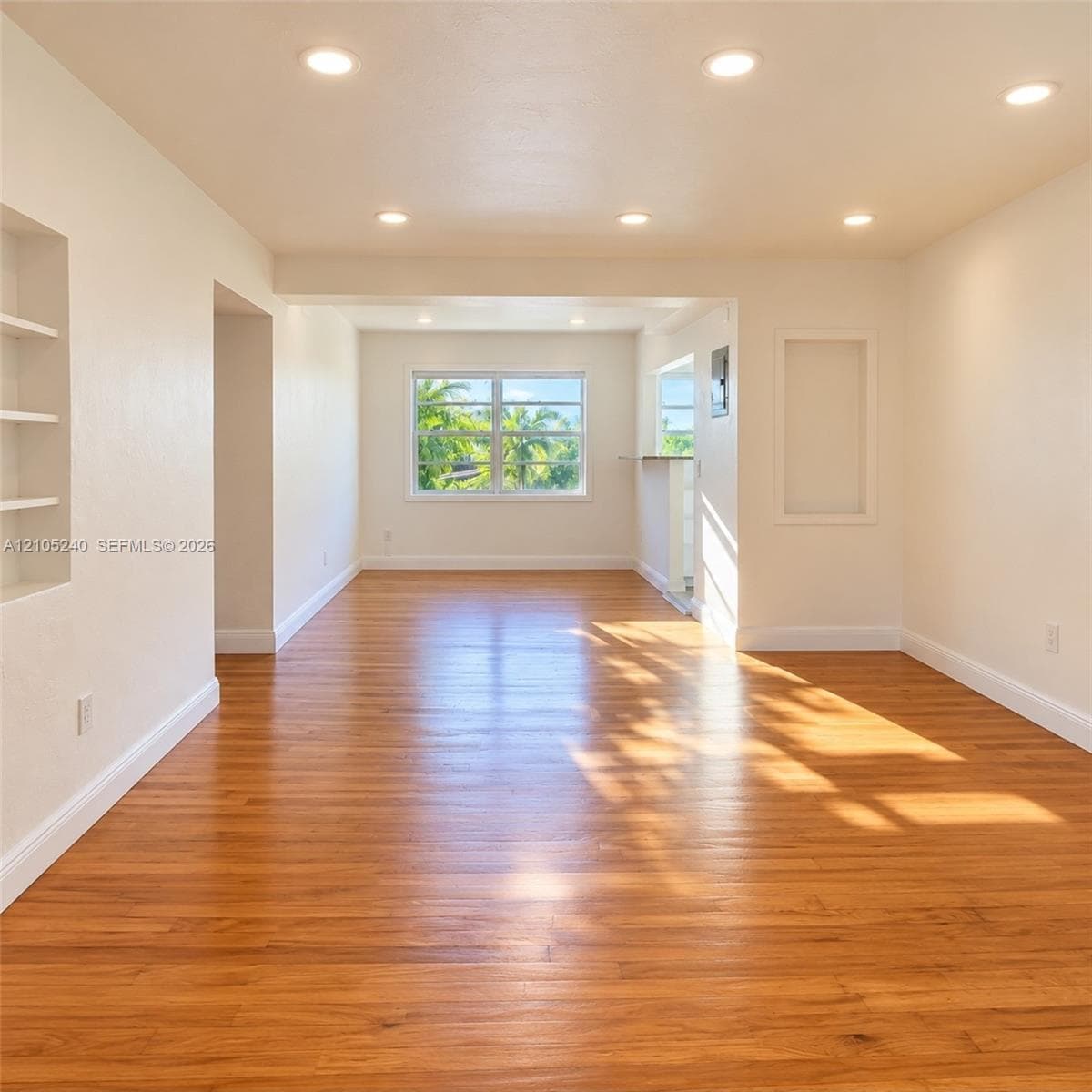 Interior space featuring wood-finish flooring, recessed lighting, built-in wall shelving, and a framed window