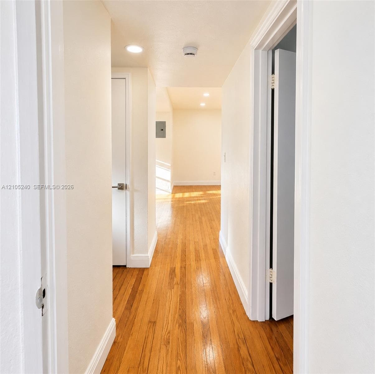 Hallway featuring wood-finish flooring, recessed lighting, and interior doors with brushed-metal hardware