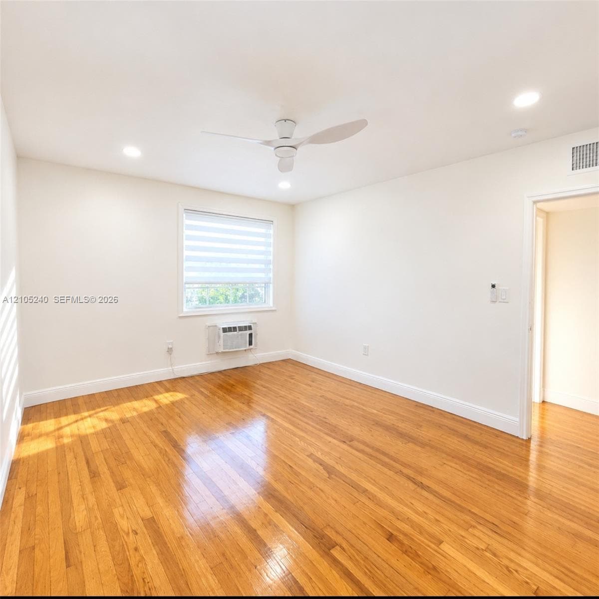 Interior space featuring wood-finish flooring, recessed lighting, a modern ceiling fan, and a window with integrated shade