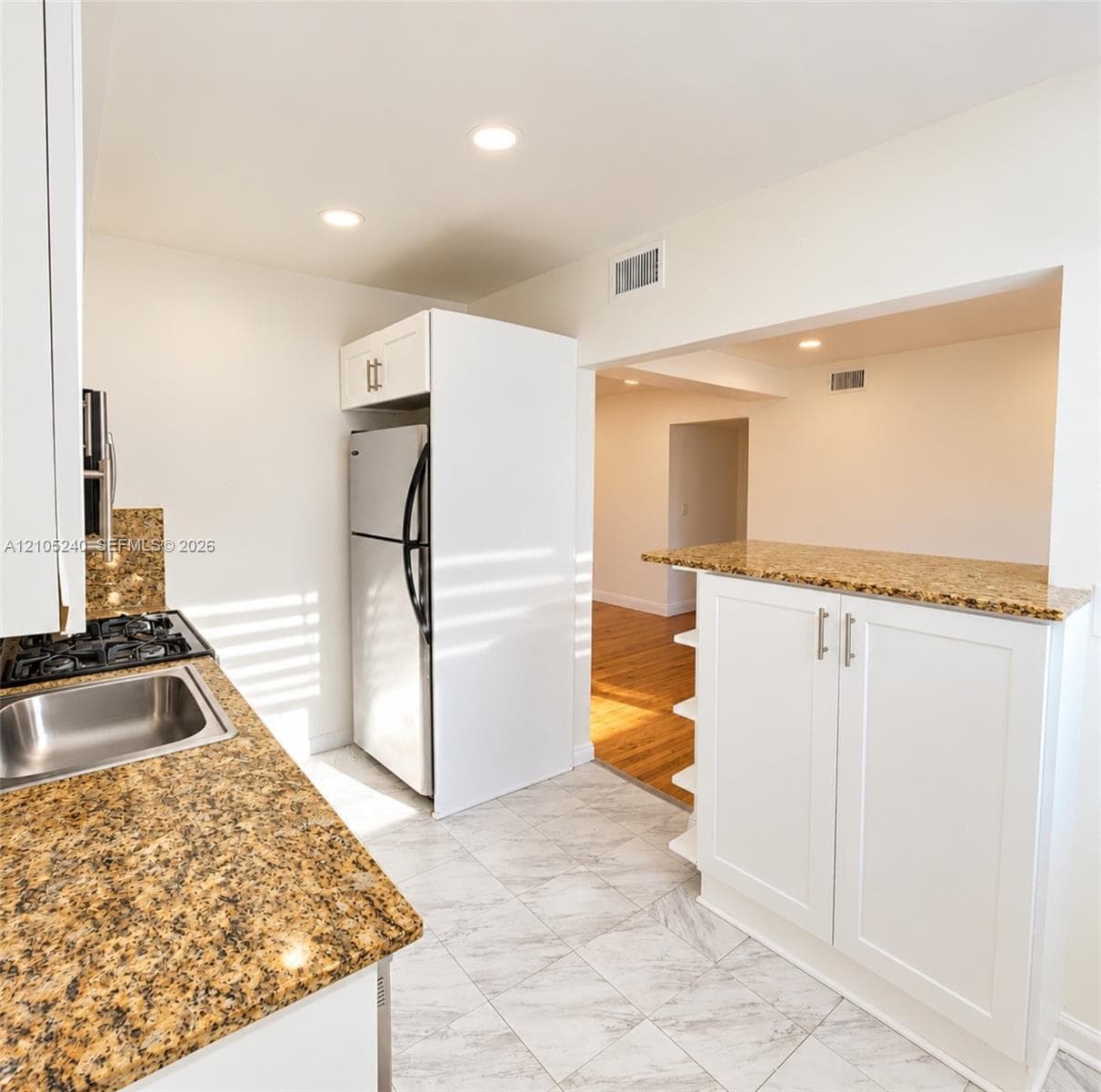 Kitchen featuring stone countertops, white shaker-style cabinetry, recessed lighting, tile flooring, and a stainless steel sink with a gas cooktop