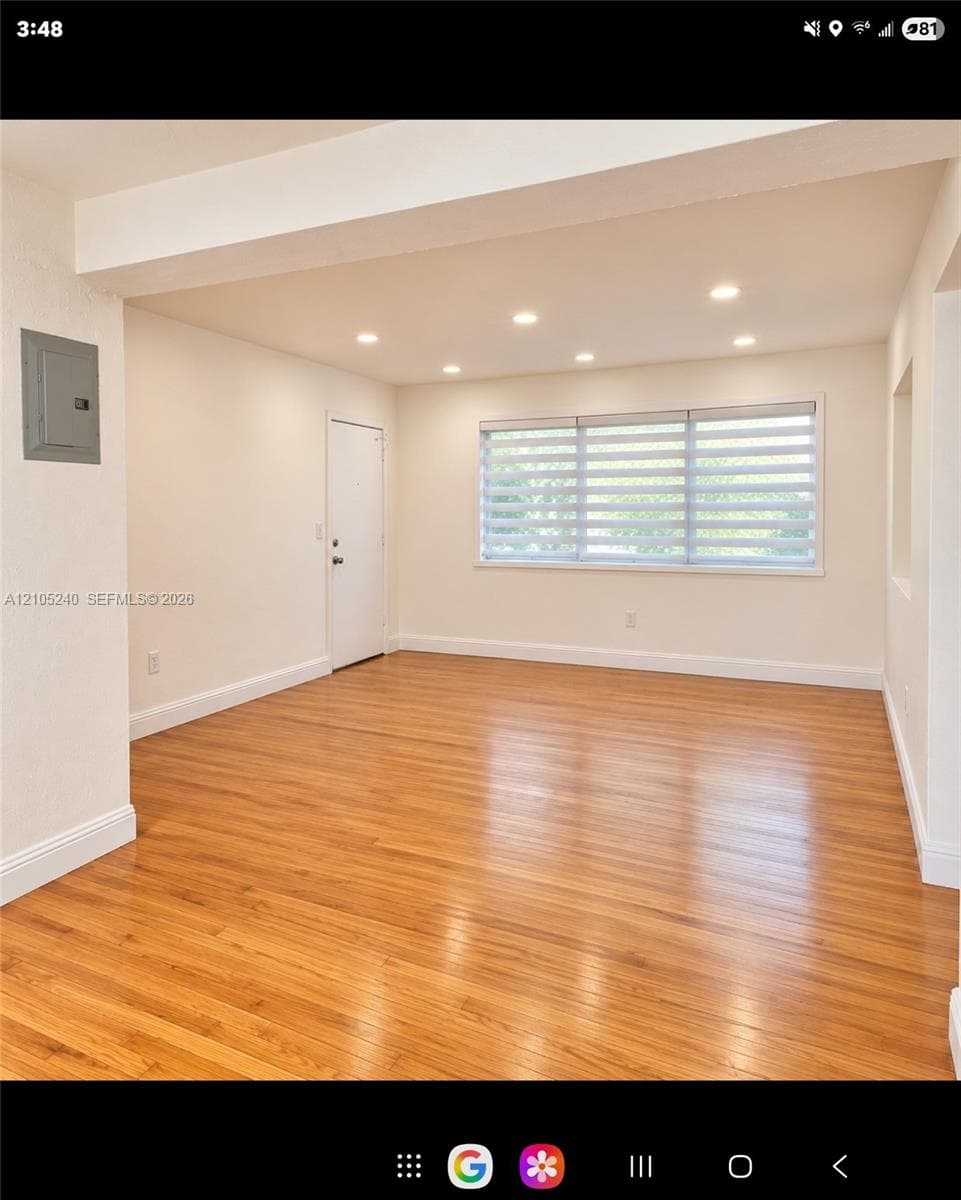 Bright interior space featuring wood-finish flooring, recessed lighting, and a large horizontal window with dual-layer shades