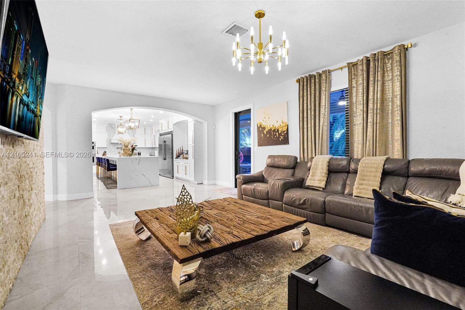 Arched entryway, polished tile flooring, stone accent wall, recessed lighting, and a modern chandelier