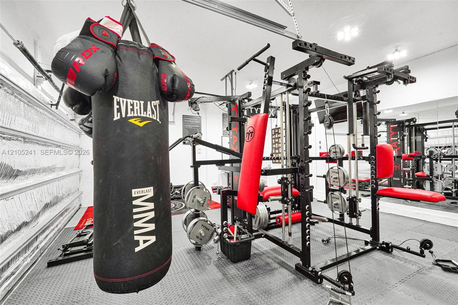 Dedicated fitness space with rubber flooring, integrated power rack, and reflective wall panels