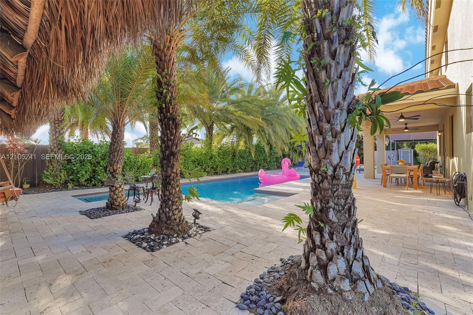 Paver patio surrounding a swimming pool with multiple palm trees