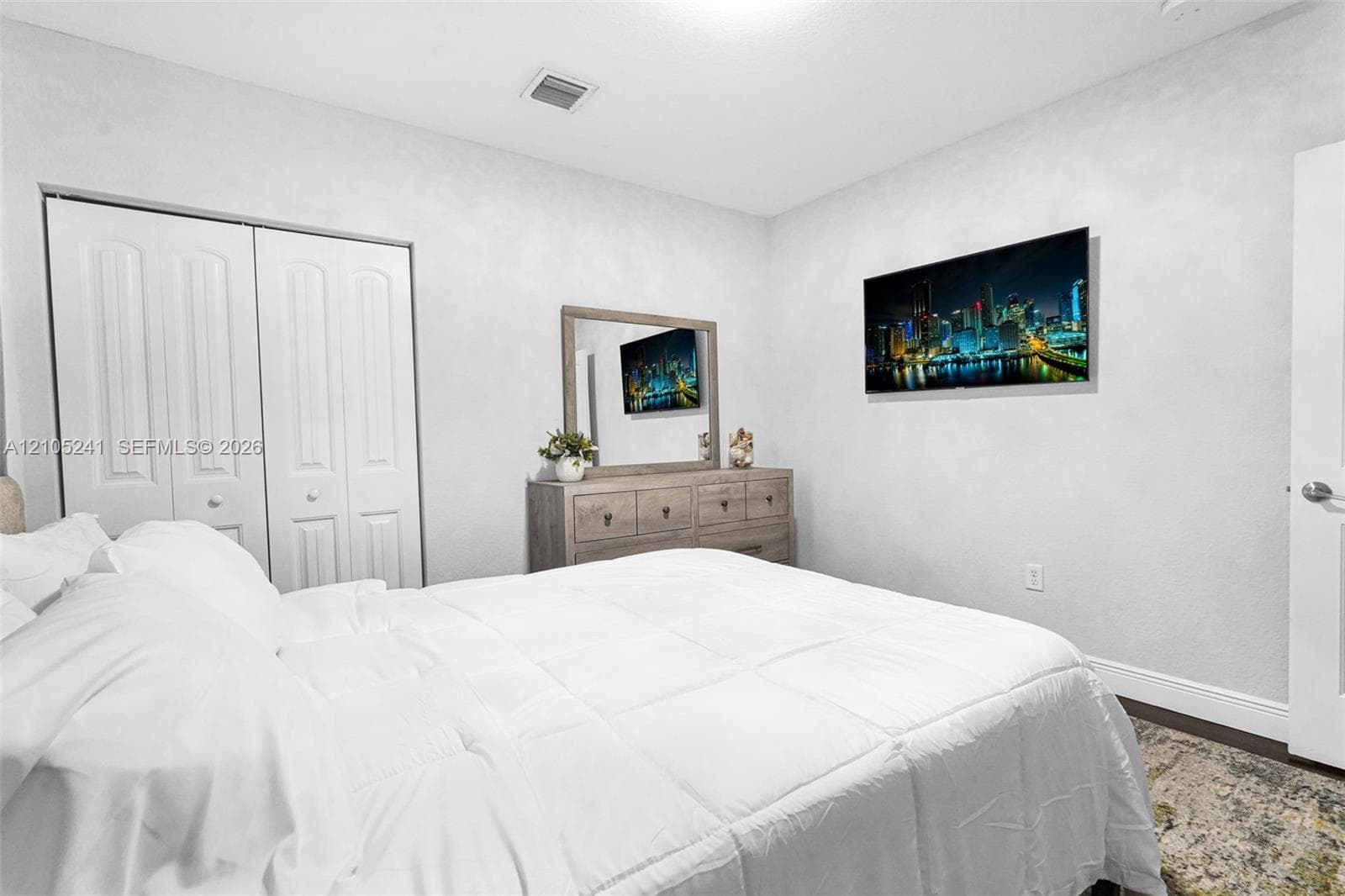 White paneled bifold closet doors, light textured walls, and wood-finish flooring