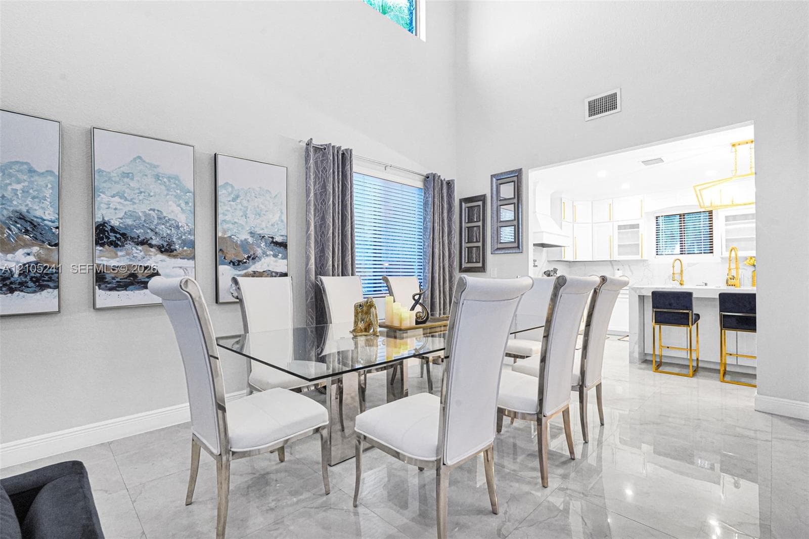 Spacious dining area featuring high ceilings, large windows with blinds, and polished tile flooring