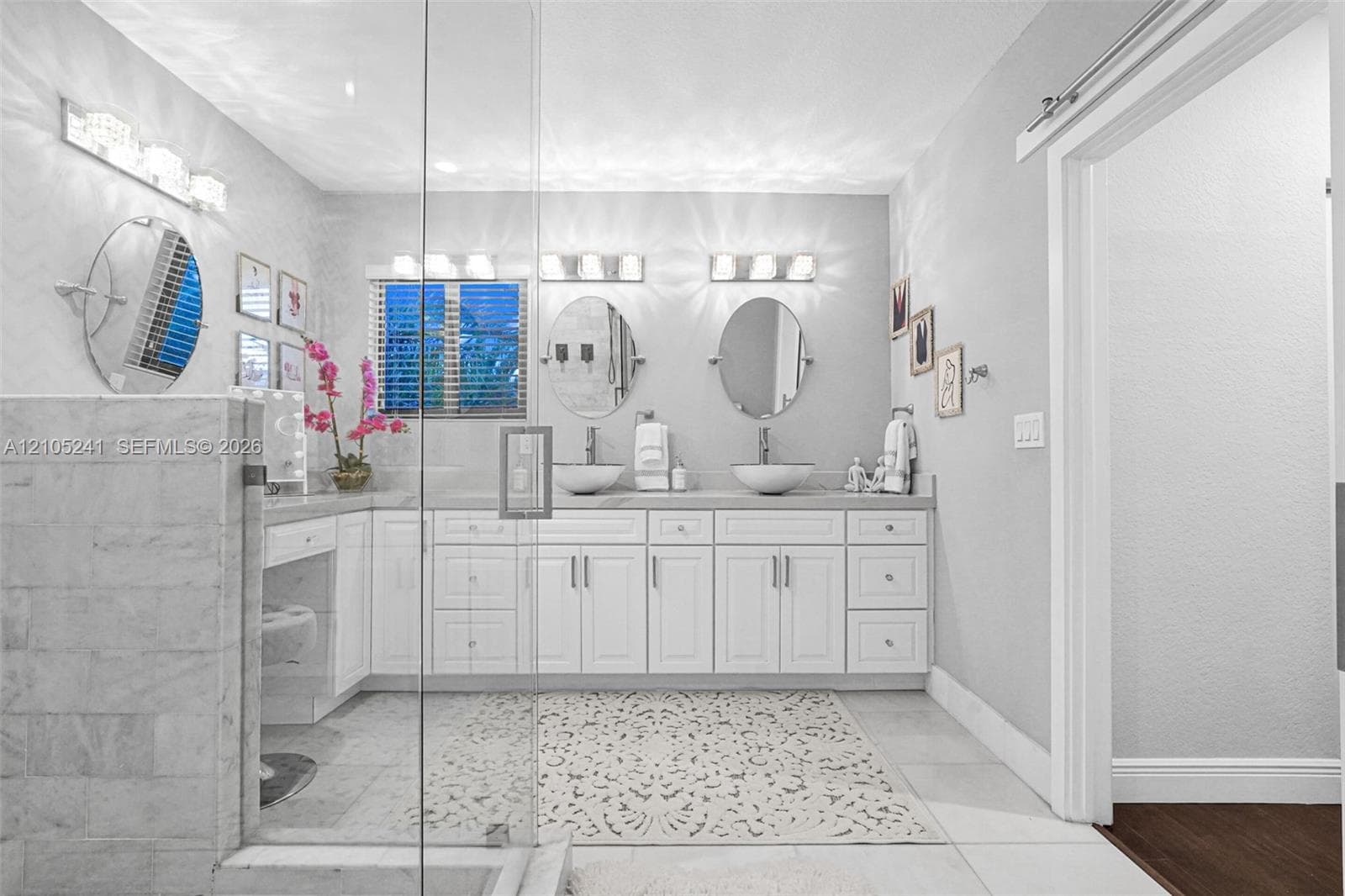 Dual vessel sinks set in an extended vanity with white cabinetry and light-toned countertops