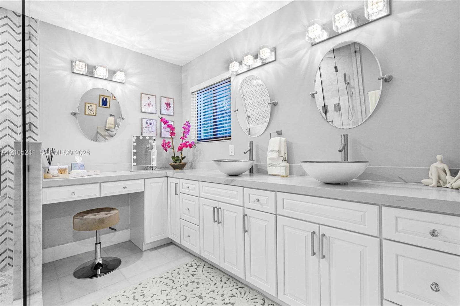 Double vanity with white shaker-style cabinetry, vessel sinks, and wall-mounted light fixtures