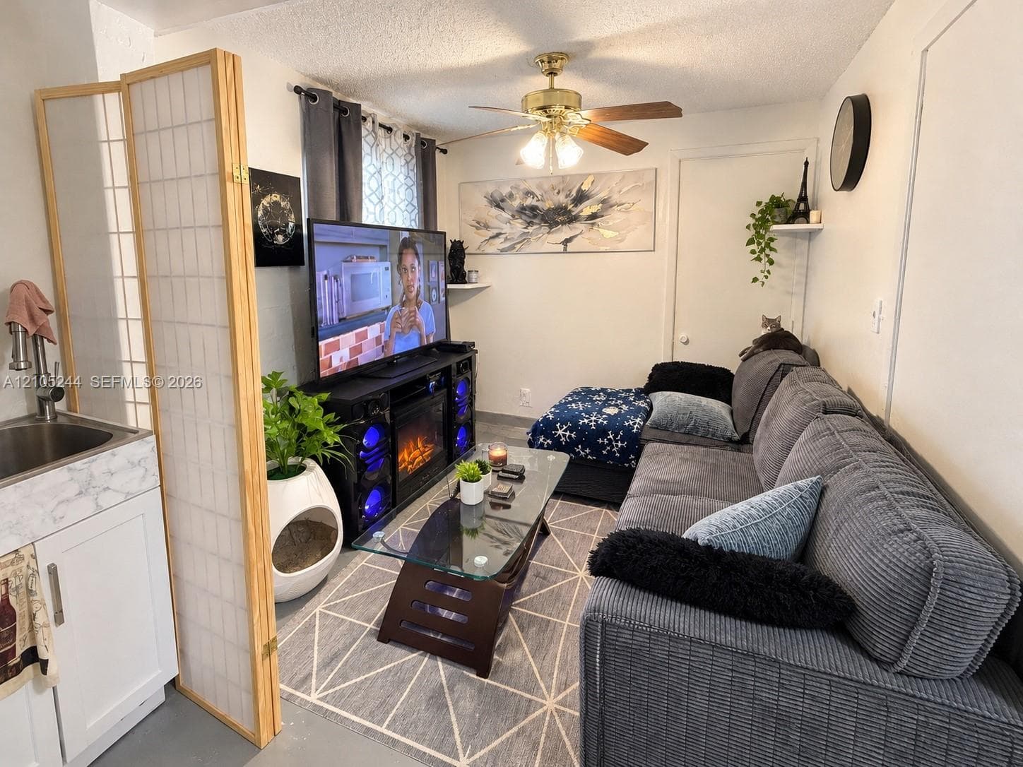 Built-in cabinetry with a stone-finish countertop, stainless steel sink, polished chrome faucet, and ceiling-mounted fan with integrated light fixture