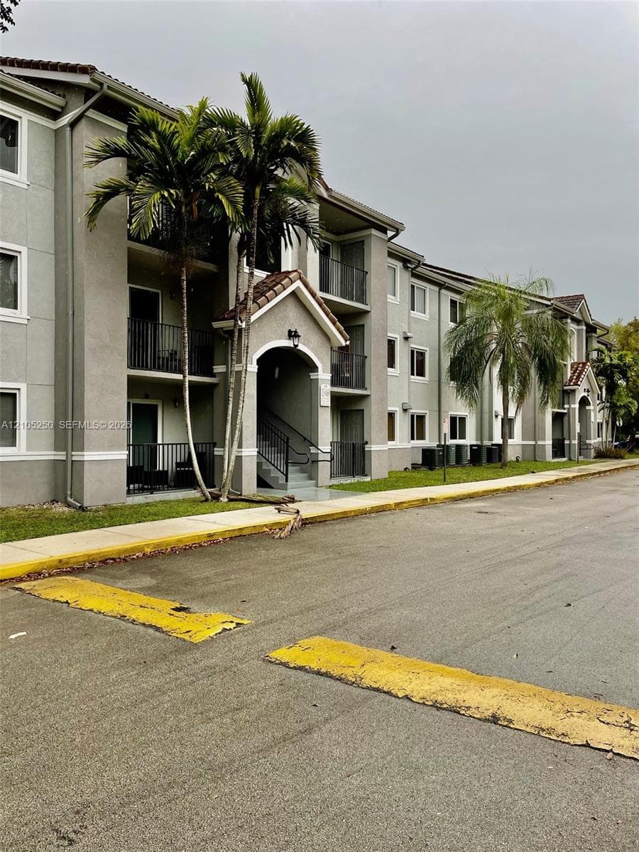 Multi-story building featuring tile roofing, stucco exterior, and black metal balconies