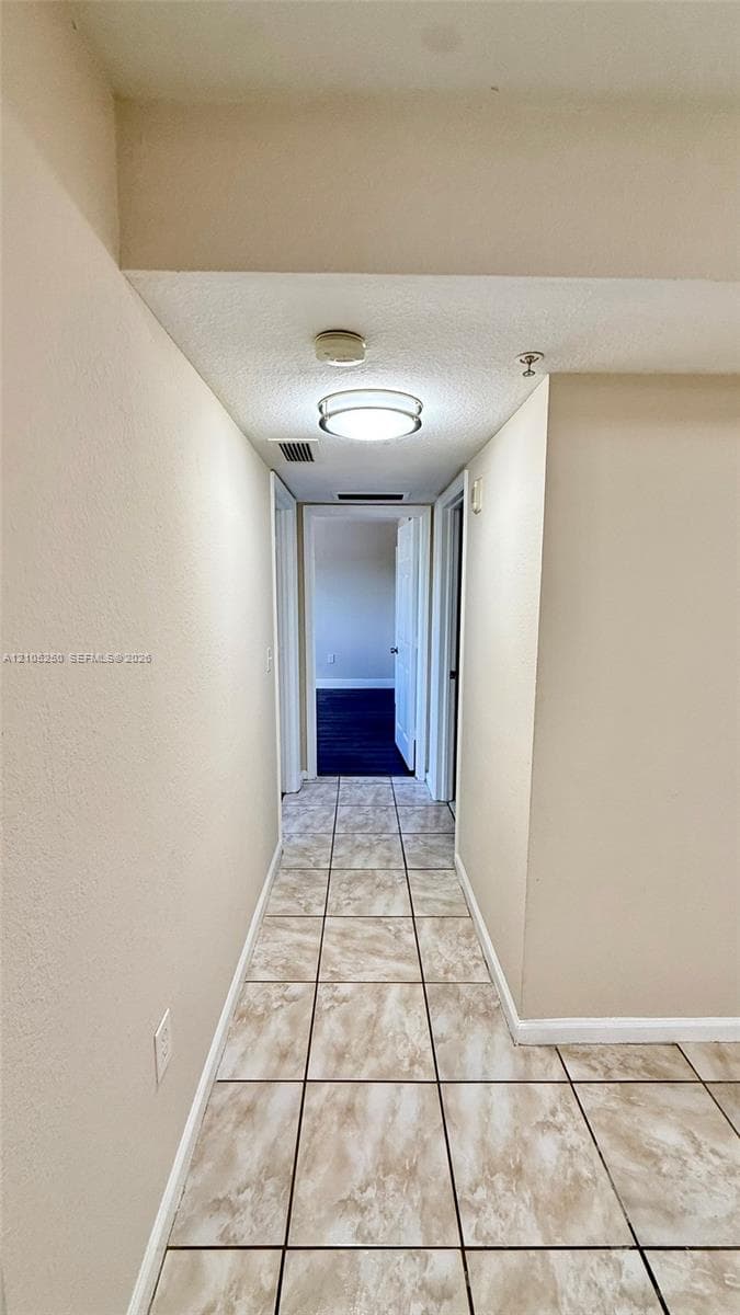 Kitchen featuring tile flooring, white side-by-side refrigerator, white microwave, white electric range, and light-toned cabinetry