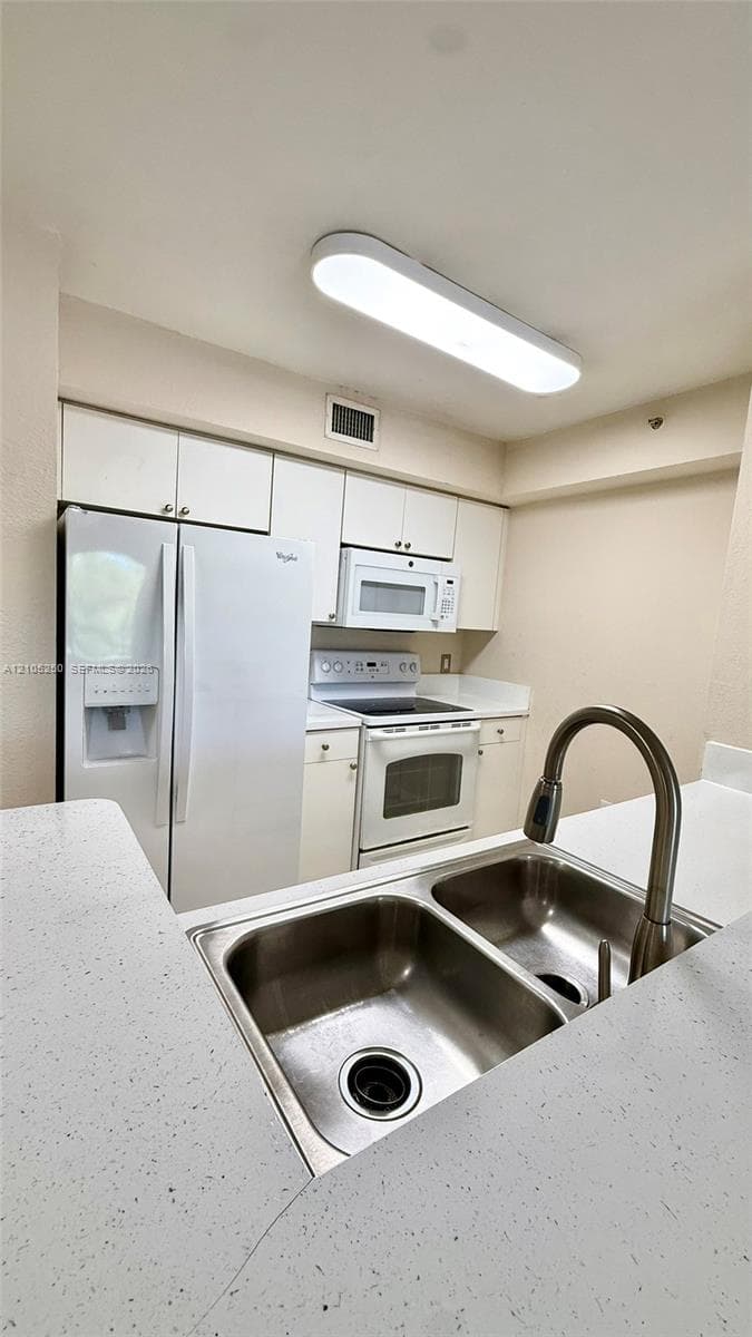 Kitchen featuring white cabinetry, a double basin stainless steel sink, a stainless steel faucet, and track lighting