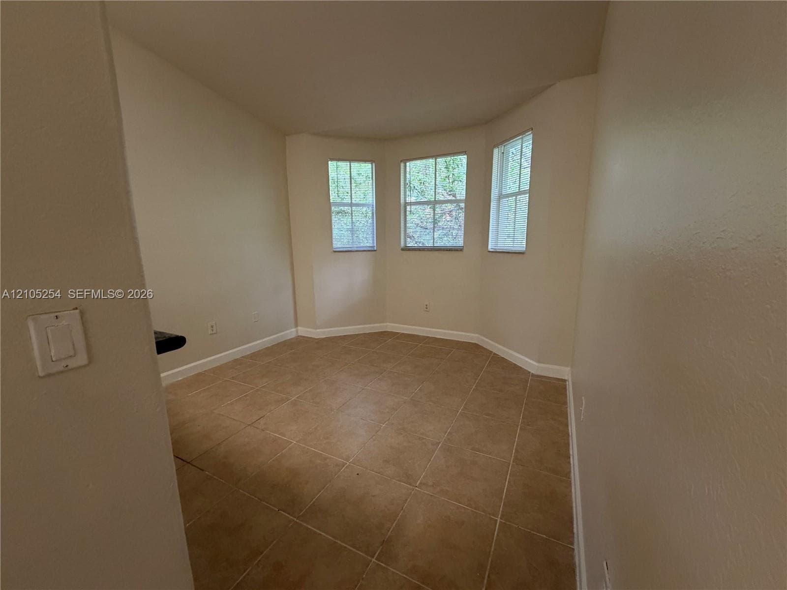 Bay window with three individual windows, tile flooring, and light neutral wall paint