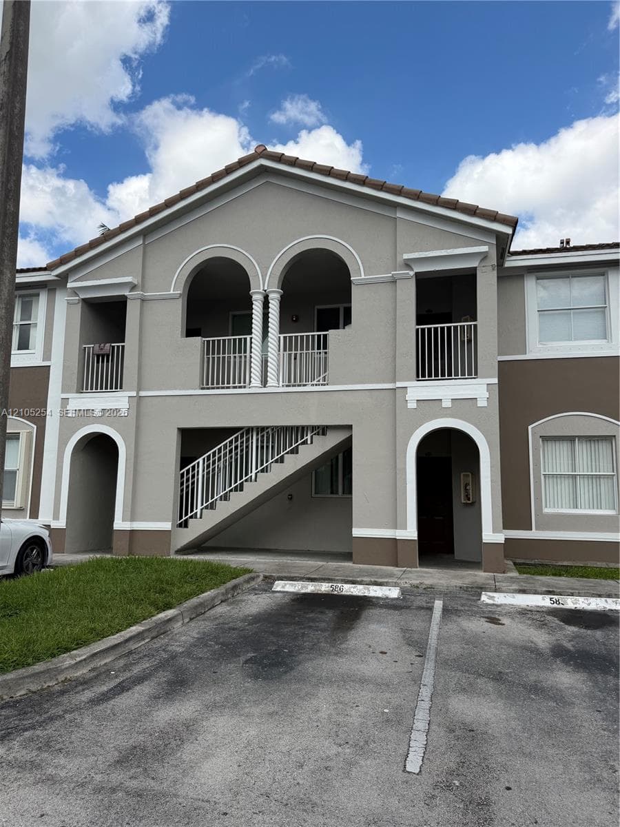 Stucco exterior with arched architectural details, tile roof, and white railings