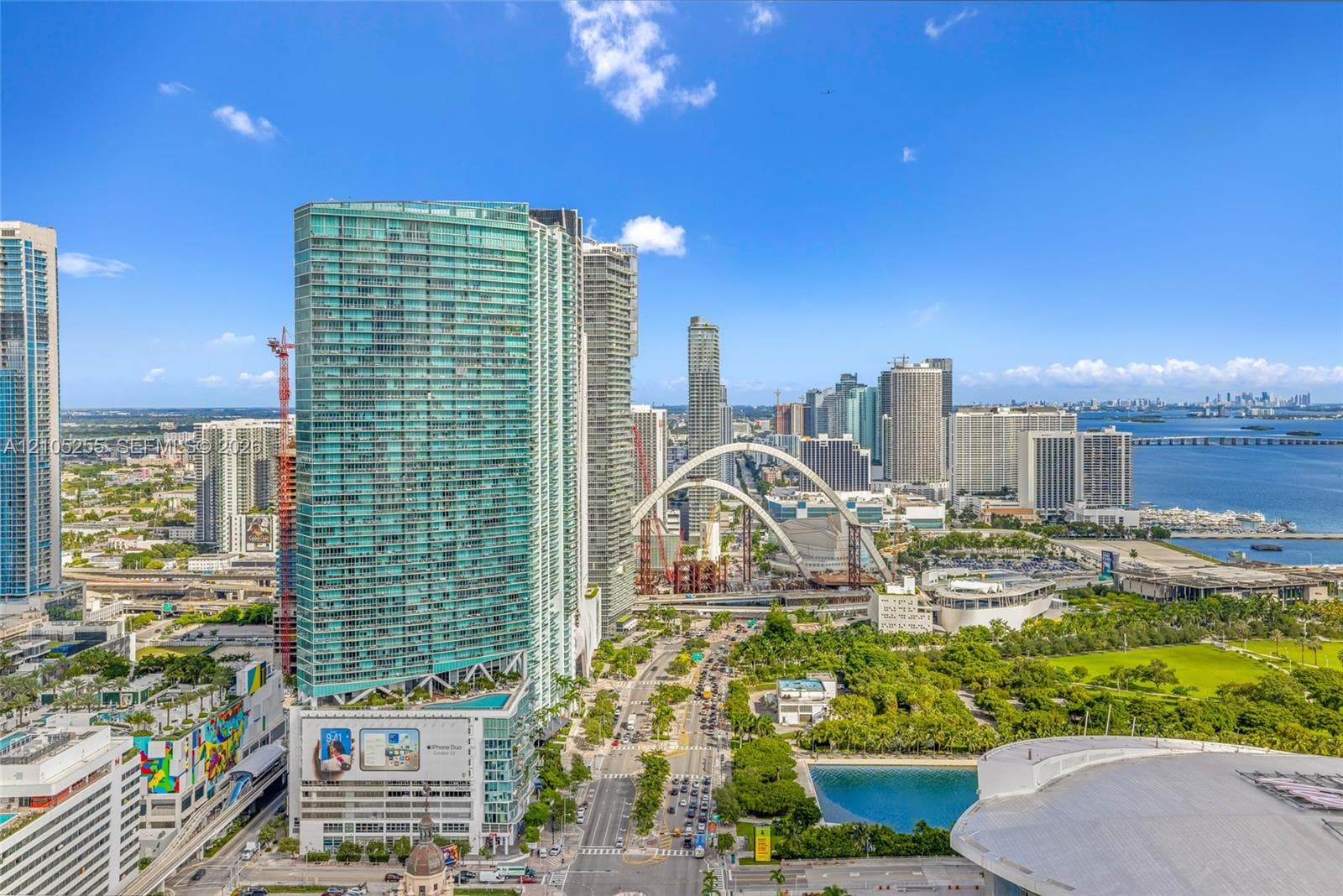High-rise tower with floor-to-ceiling windows, glass facade, urban skyline setting, proximity to coastal waters, and extensive green space
