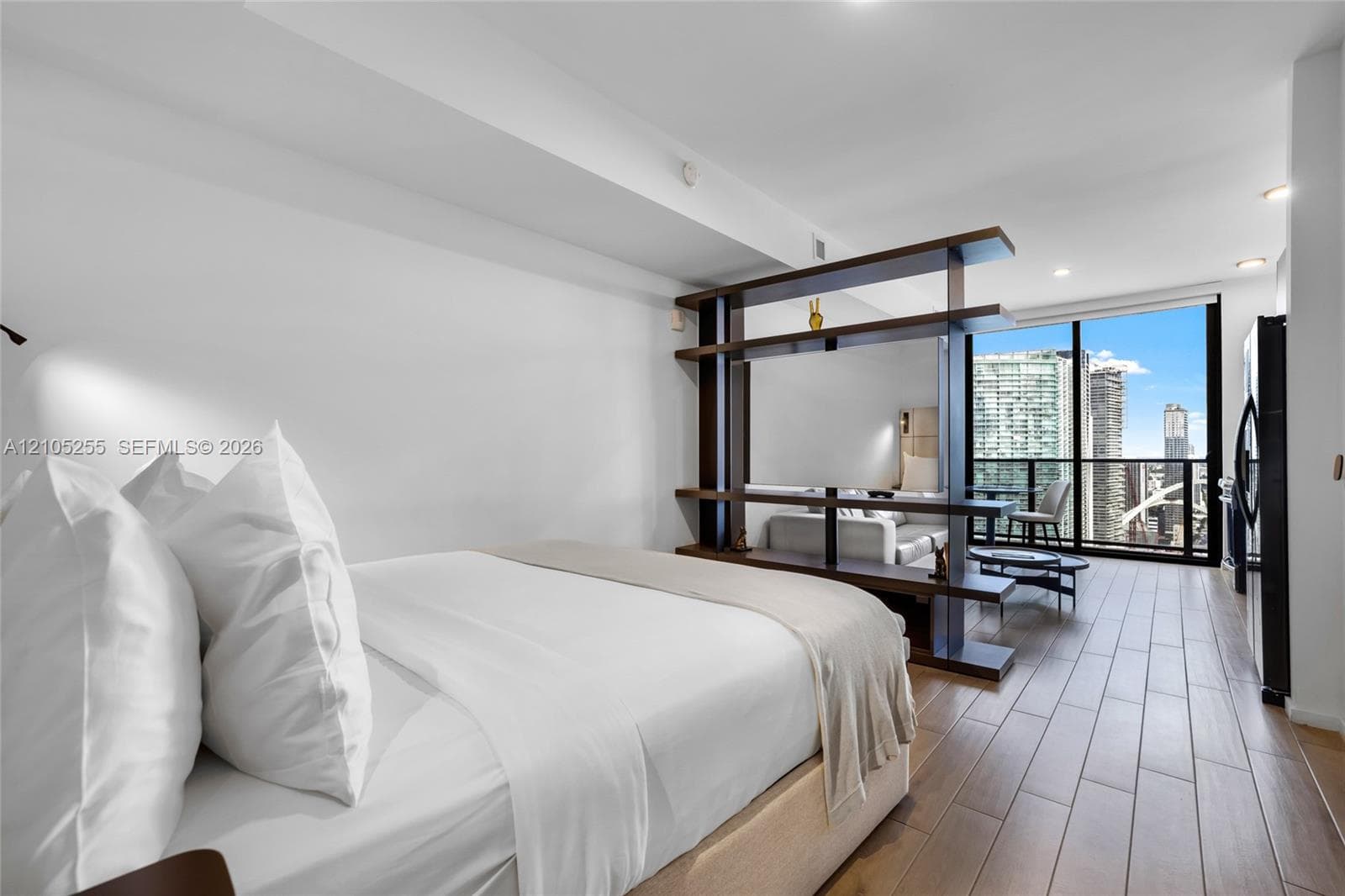 Floor-to-ceiling windows, wood-finish flooring, built-in dark-toned shelving partition, and recessed ceiling lighting