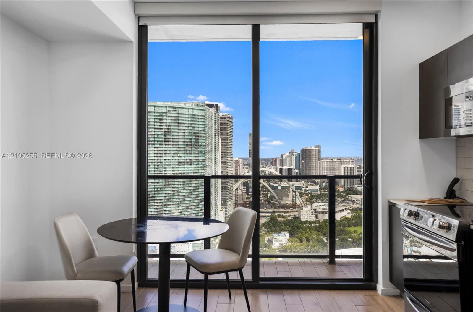 Floor-to-ceiling sliding glass door, wood-finish flooring, and high-rise urban scenery