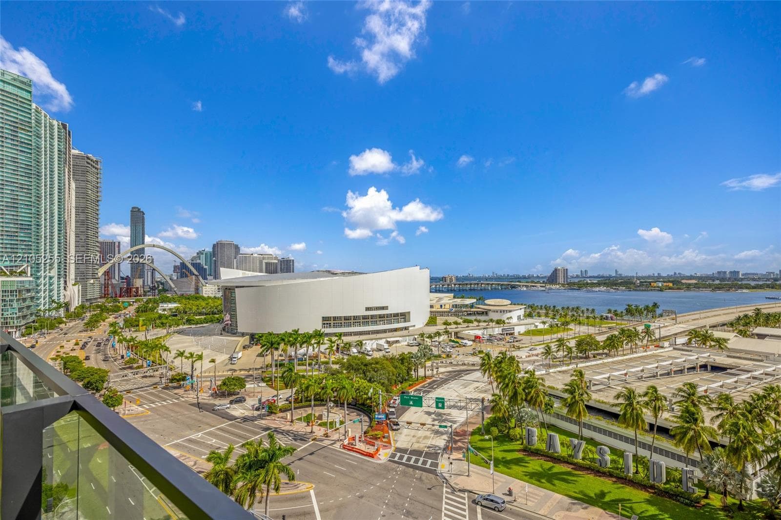 Private balcony with glass railing overlooking the urban skyline, waterfront, and surrounding park landscape