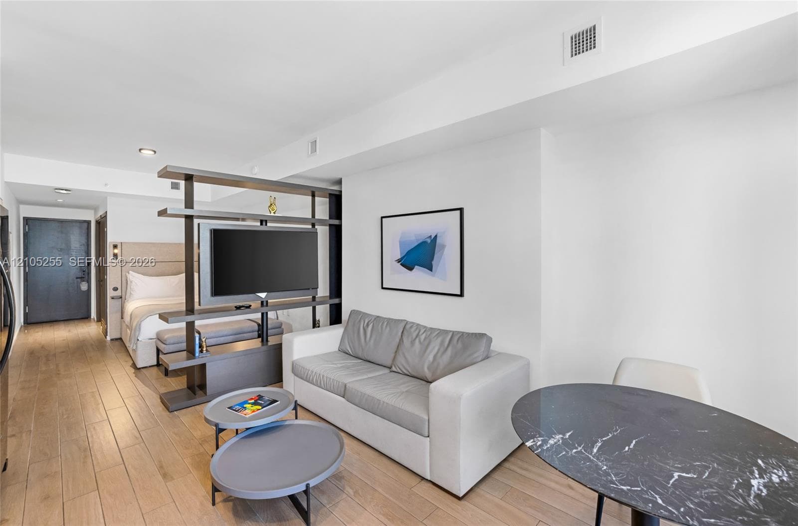Wood-finish flooring throughout, featuring a built-in shelving unit with an integrated television mount