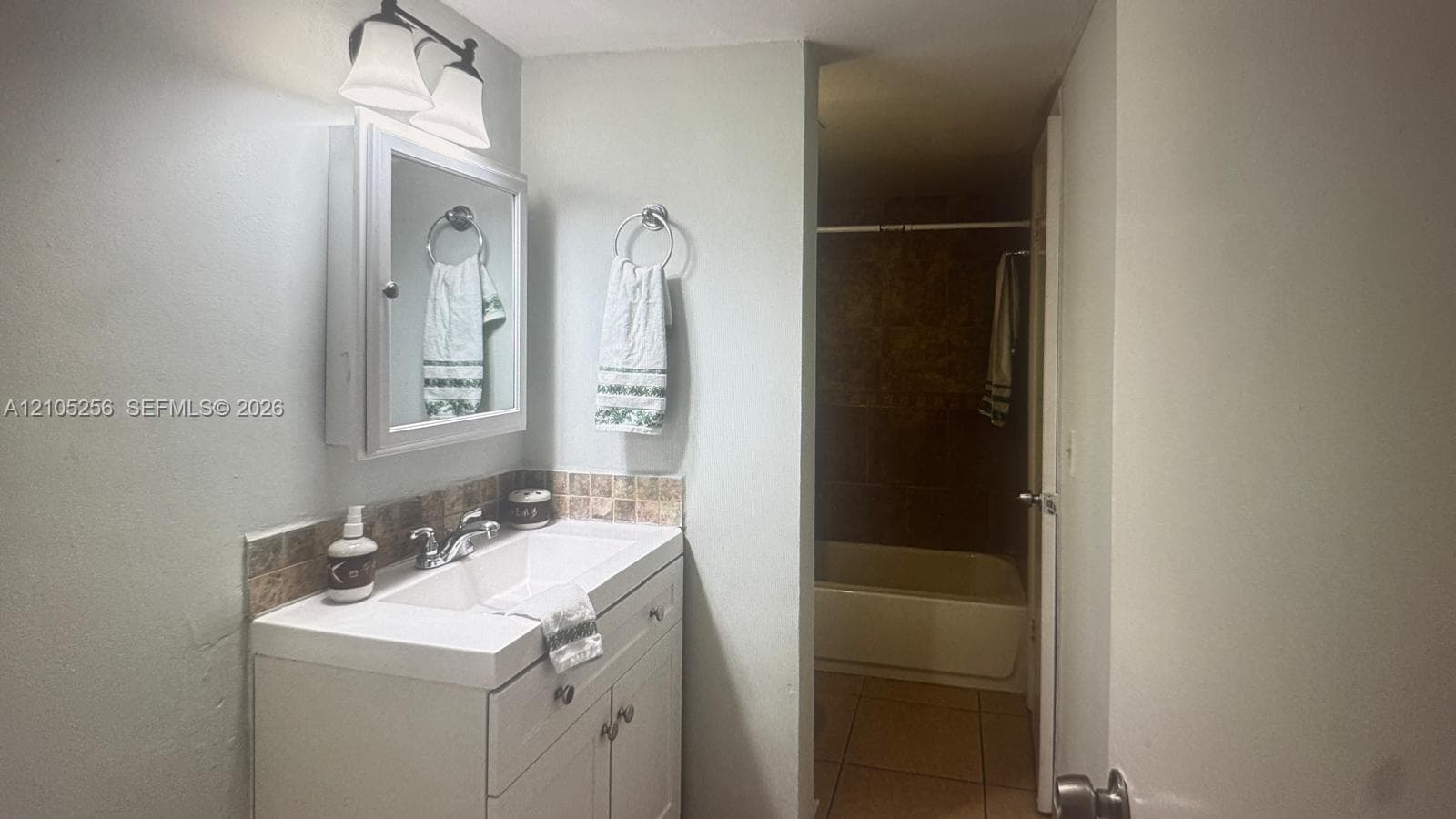 White vanity with integrated sink, chrome faucet, medicine cabinet, and tiled backsplash