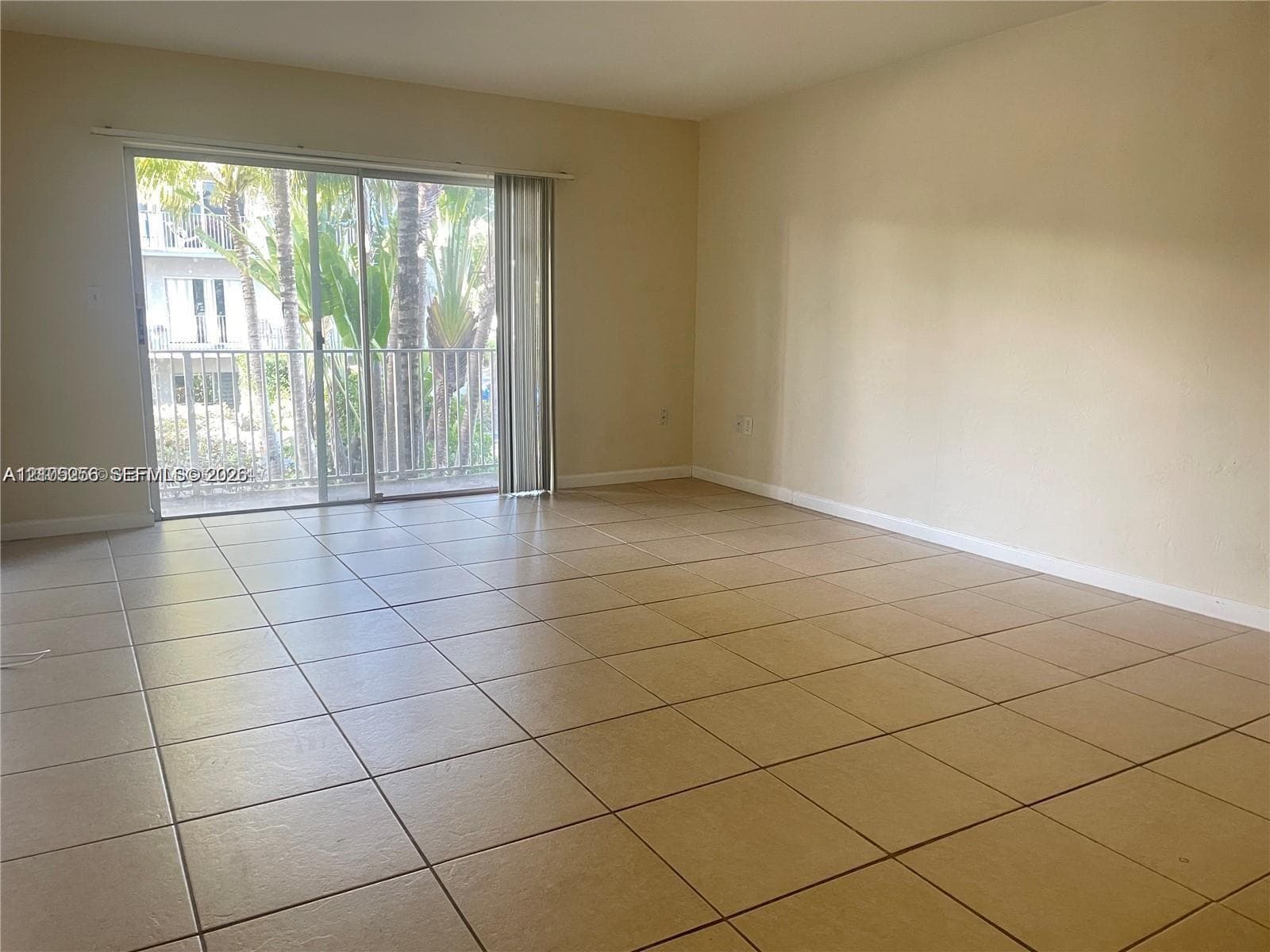 Interior space featuring large-format ceramic tile flooring, neutral wall tones, and floor-to-ceiling sliding glass doors opening to a private balcony